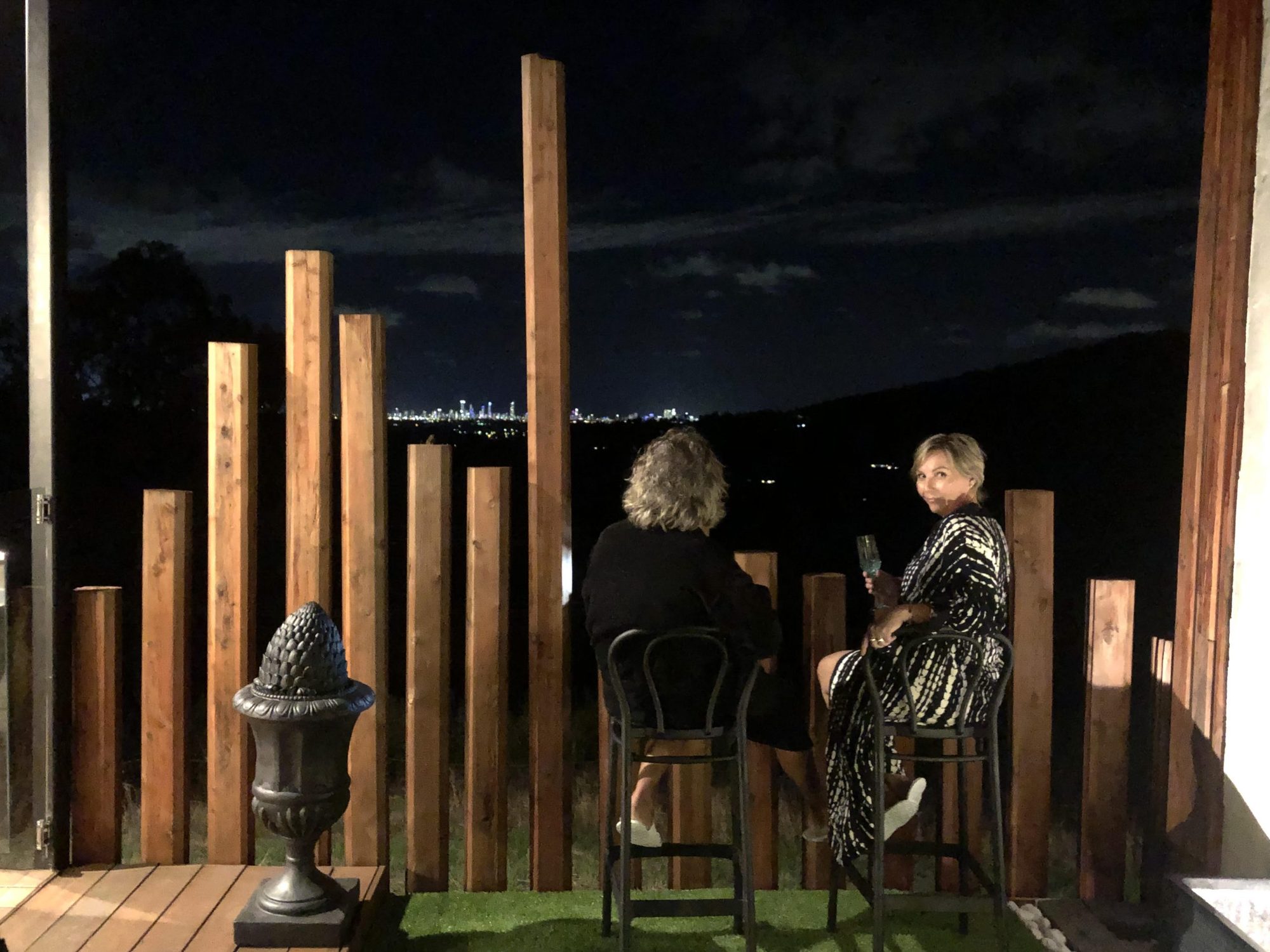 Guests on the villa deck at night with city lights in the distance