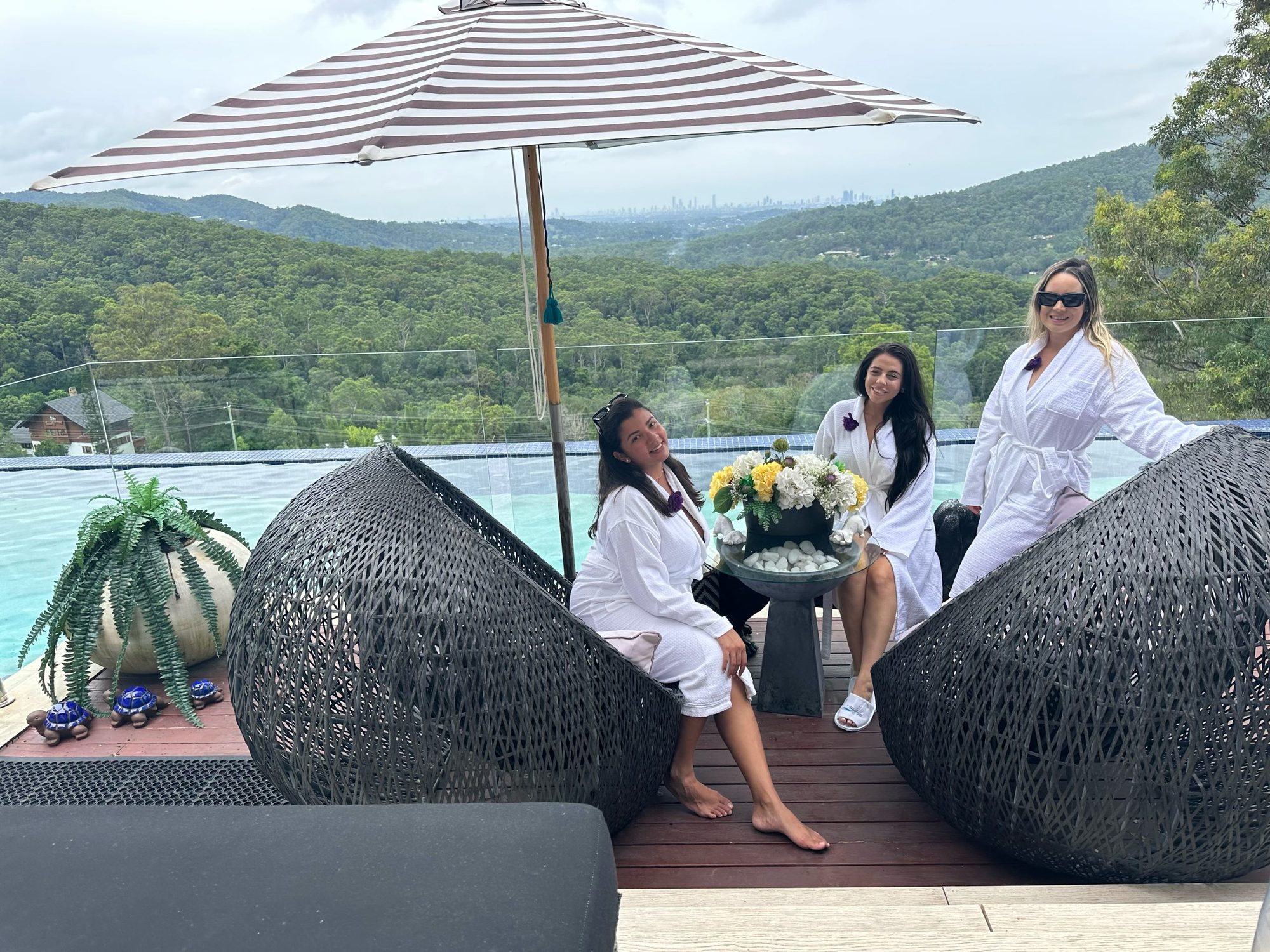 Friends in robes relaxing in egg chairs by the pool