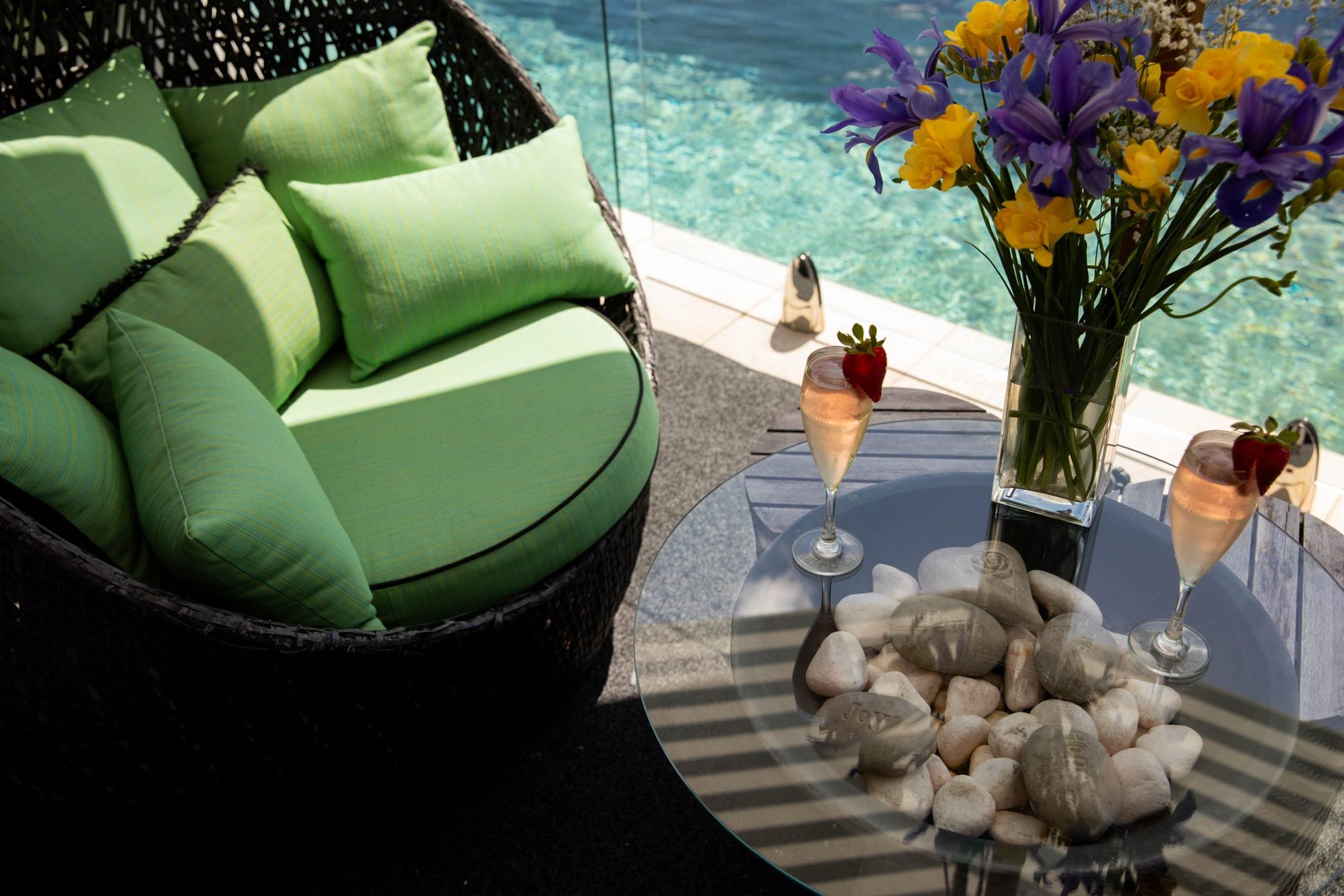 Green wicker lounges with flowers by the pool