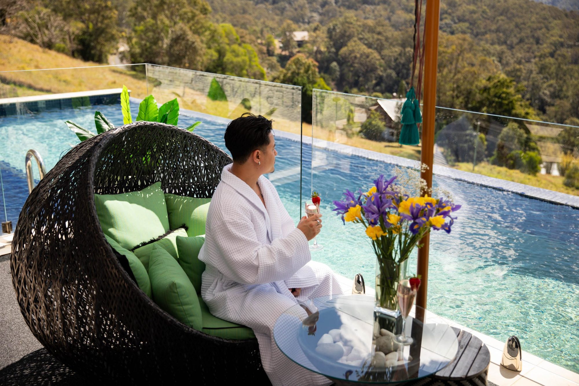Guest in a robe in an egg chair by the pool